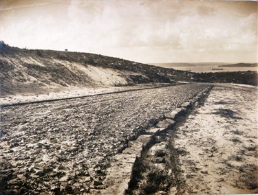 Construction of Birriga Road, previously known as Tram Road, or Road A. Handwritten on reverse: ‘Slope of cutting also gutter extreme end of road A. Sharp bend’.   One of a series of photographs taken of the construction of Birriga, Bundarra and Banksia Roads, and Benelong Crescent, formed as part of the Bellevue Hill Bondi Estate. Woollahra Libraries Digital Archive PF004648a