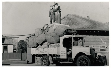 Volunteers with the Woollahra branch of the National Emergency Services distribute sand bags from the top of a vehicle.