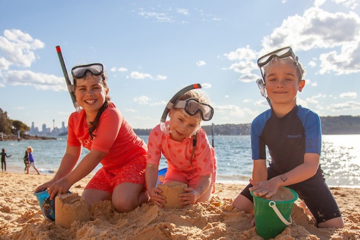 Two girls and one boy building a sand castle