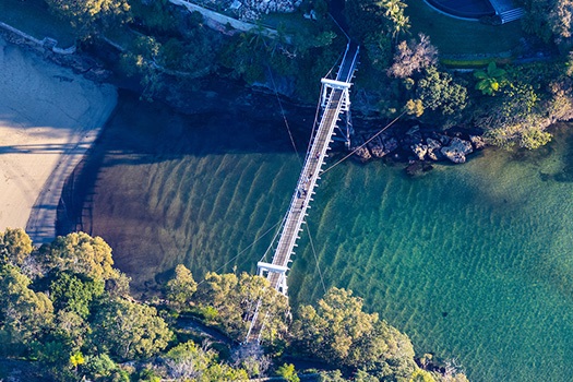 Aerial drone shot of Parsley Bay suspension bridge and beach