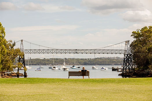 Man sitting on park bench looking at the Parsley Bay Bridge