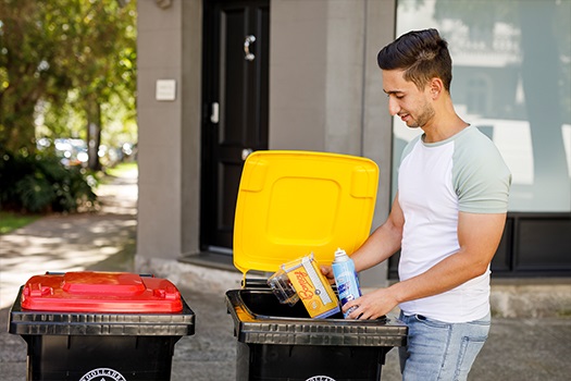 Man putting items into yellow lid recycling bin