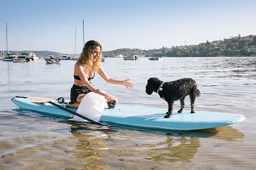 Woman on a stand up paddle board with her dog