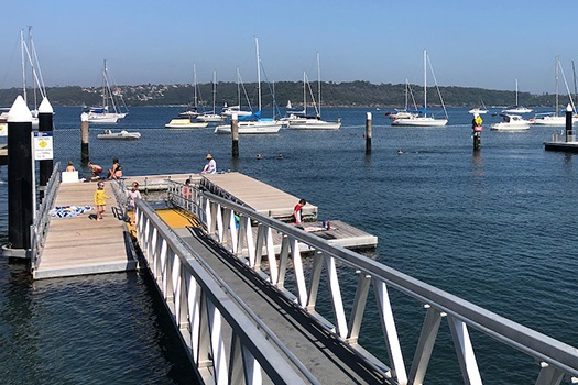 Children playing on the pontoon at Watsons Bay Baths, with ocean in the background