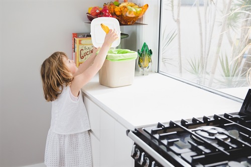 Girl putting food scraps into caddy bin